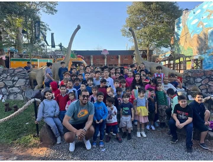 Un grupo de niños y adultos durante una visita a un espacio recreativo con dinosaurios.